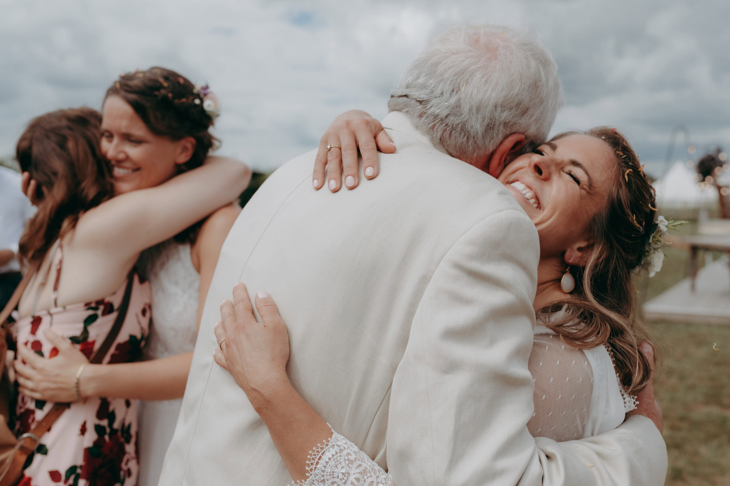 2 brides hugging parents at LGBTQ wedding in Cambridge