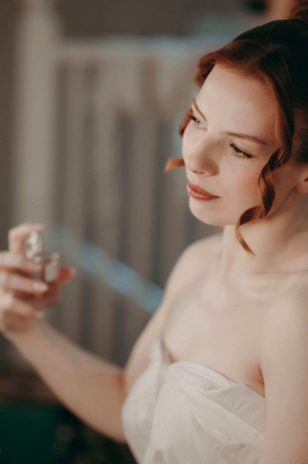 bride spraying on perfume during preparations at Gaynes Park wedding