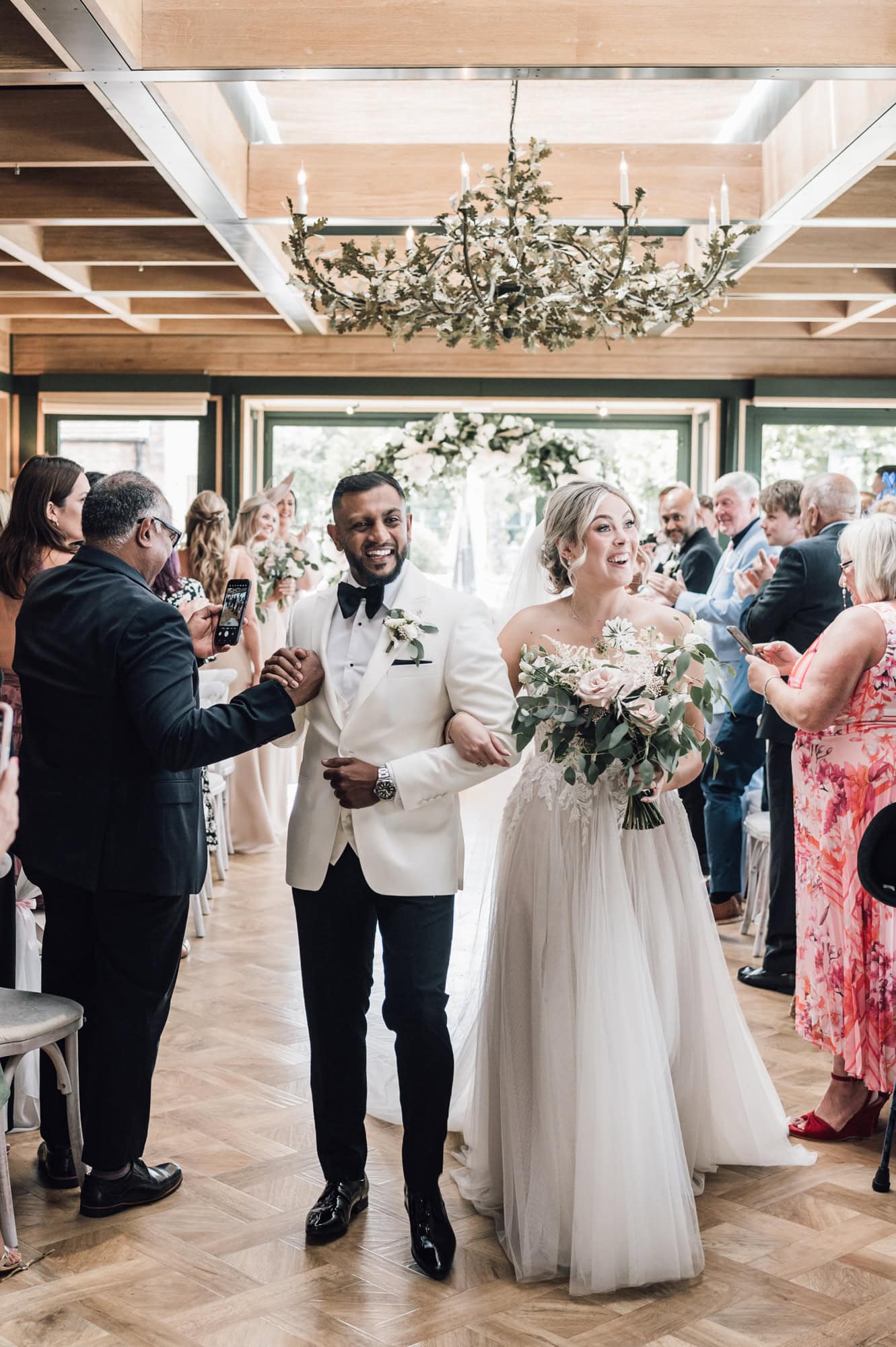 Happy bride and groom walking the aisle in stylish wedding ceremony at The Old Hall in Ely