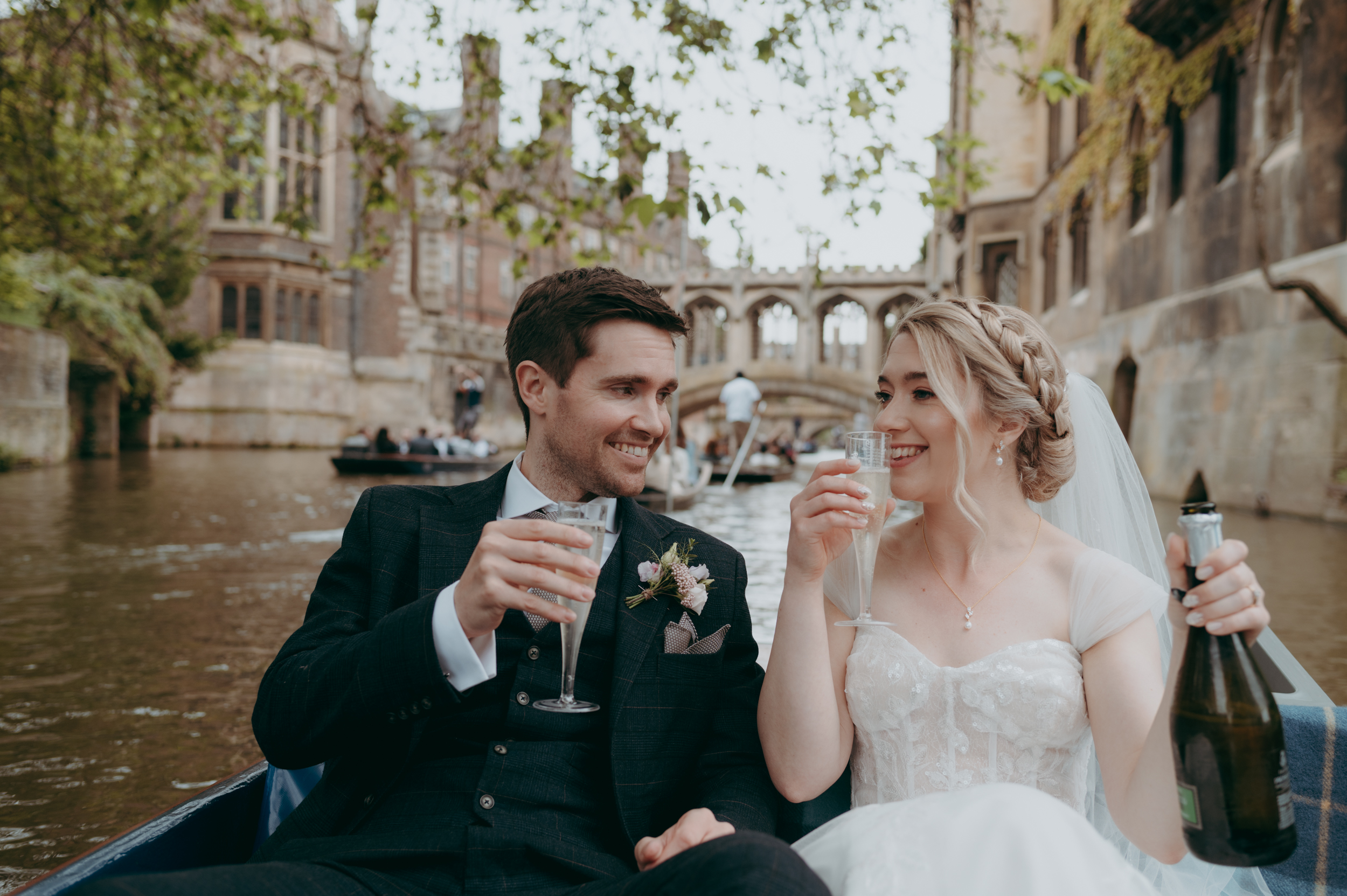 Newlywed couple drinking champagne while punting on the river Cam in Cambridge