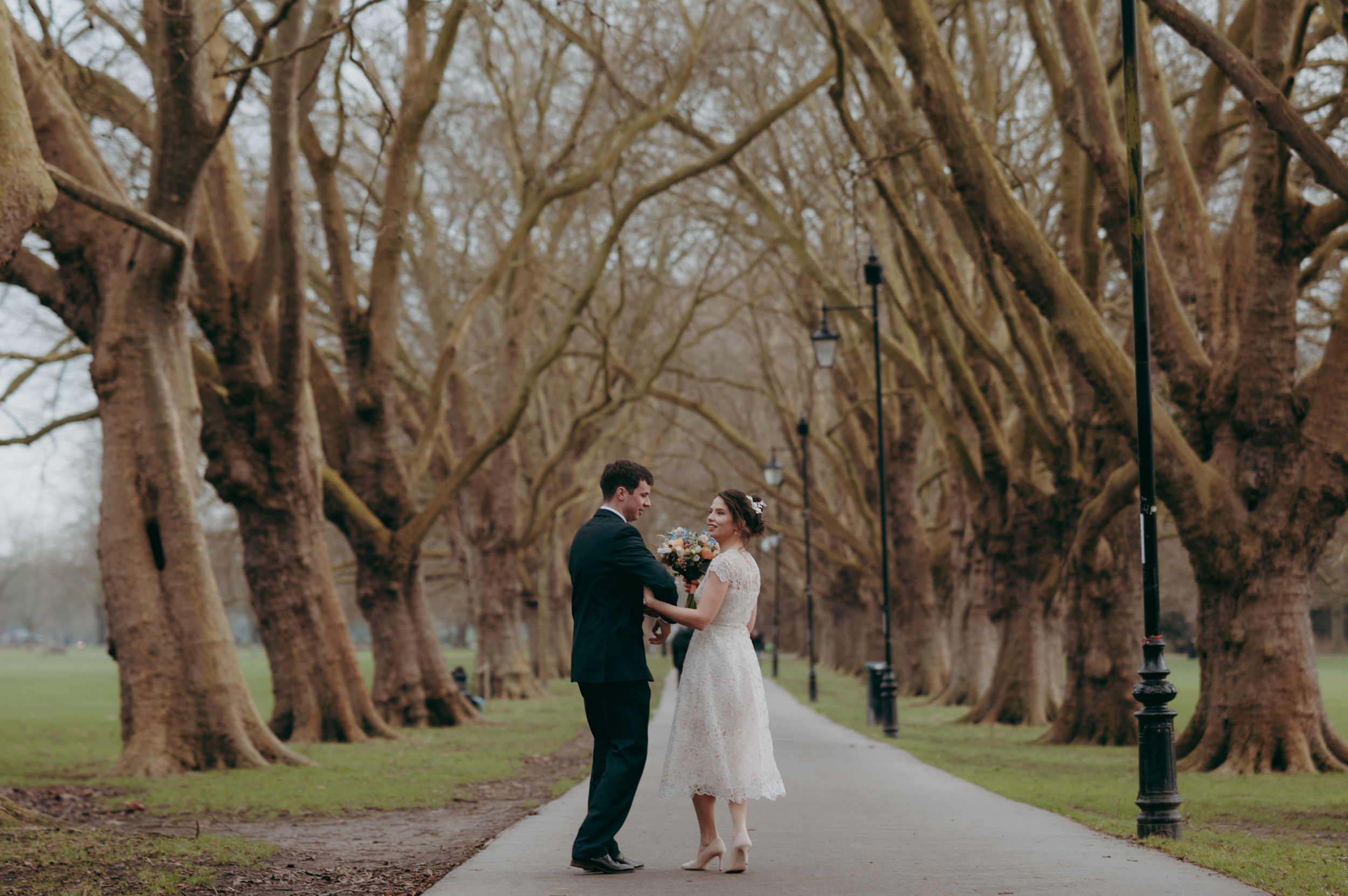 Newlywed couple walking together during wedding in Cambridge across Jesus Green in Winter
